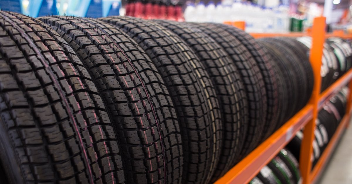 A long line of tires on a rack. The tires that are further away are smaller than the ones in front of them.