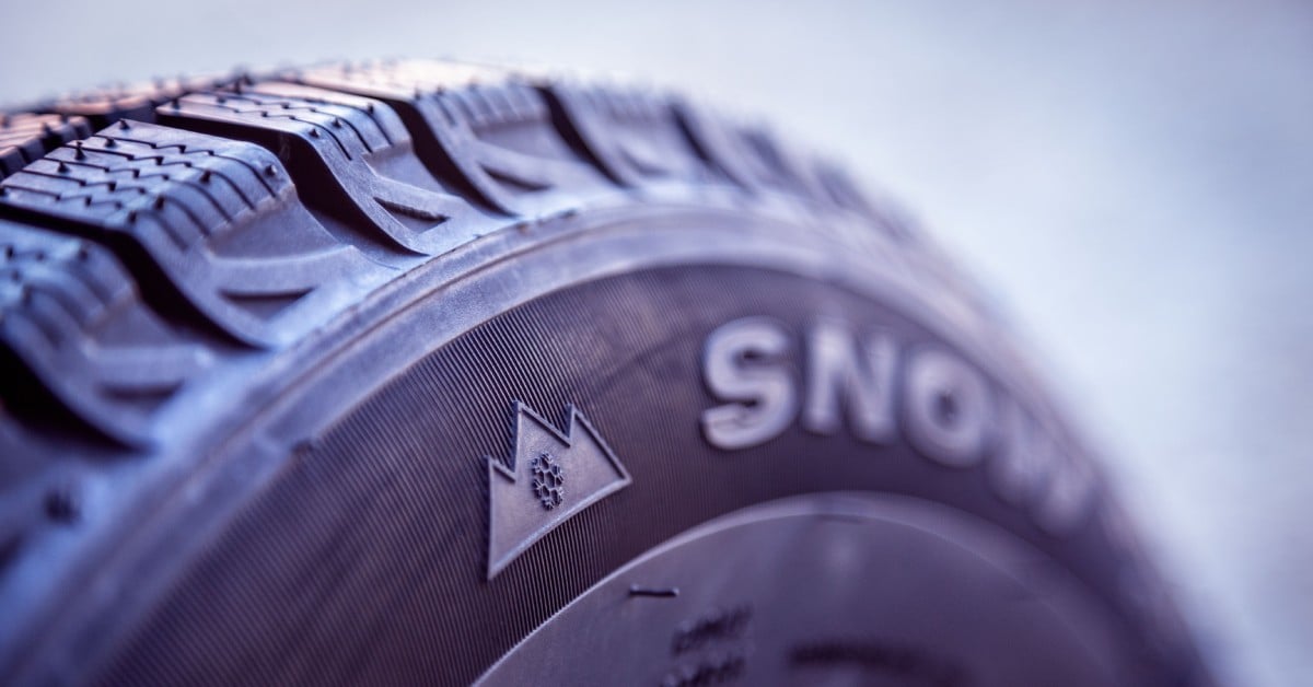 A new, clean winter tire for a car. The tire has text across its side that reads “Snow” in big letters.