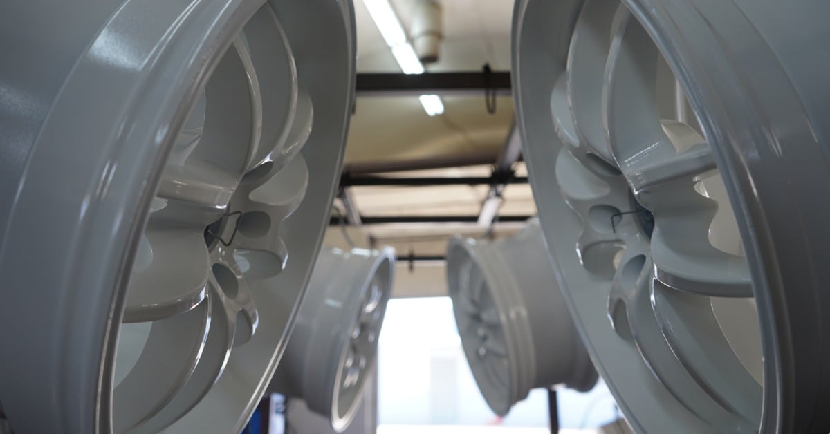 Powder-coated vehicle wheels hang in a room during the curing process for a long-lasting, durable finish.
