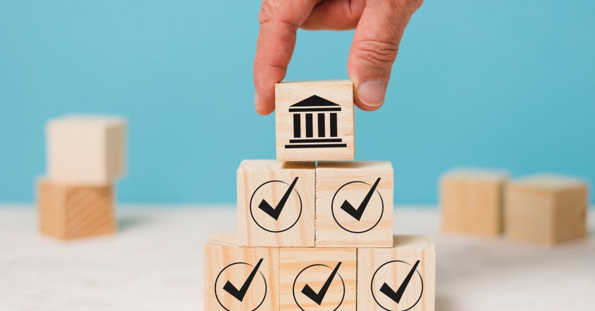 3 Tire Disposal Options Every Driver Should Know A hand places a building icon block on top of a pyramid of wooden cubes printed with checkmarks on a blue background.