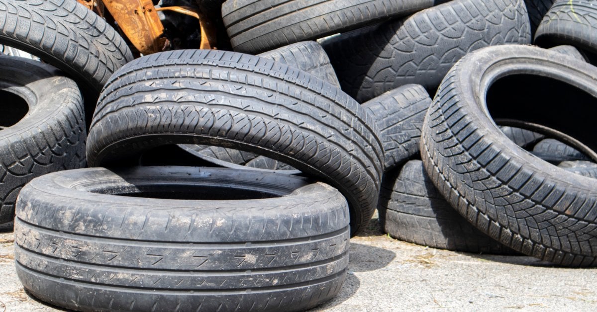 A large outdoor pile of worn and discarded passenger car tires collected at a tire recycling or waste disposal site.