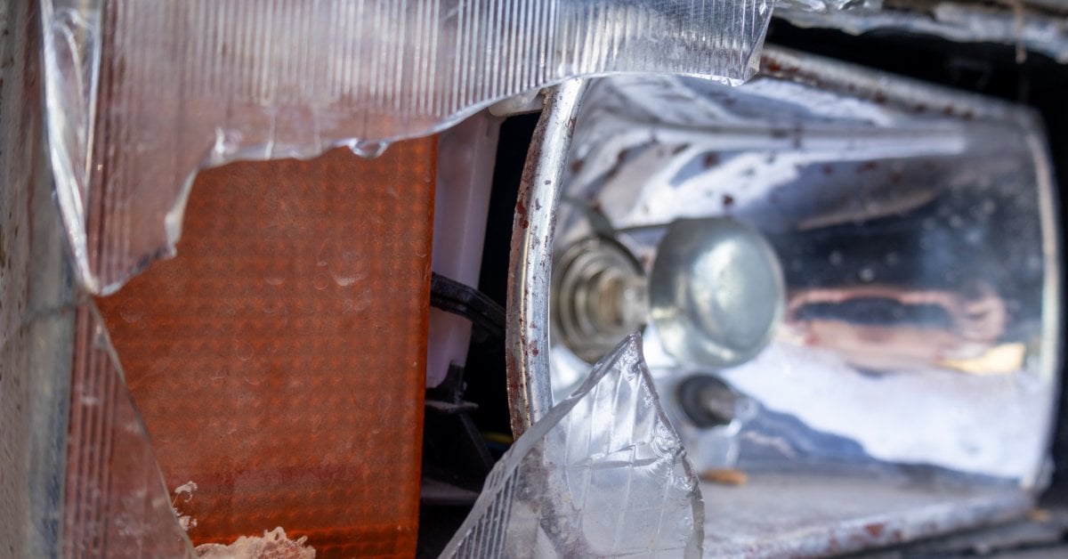 When to Repair vs Replace Your Car Headlights A shattered car headlight housing with broken lens fragments exposing the internal bulb and wiring components.
