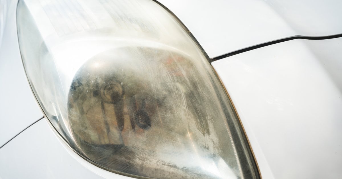 When to Repair vs Replace Your Car Headlights A cloudy, yellowed car headlight lens on a white vehicle, showing signs of UV damage and haze buildup.